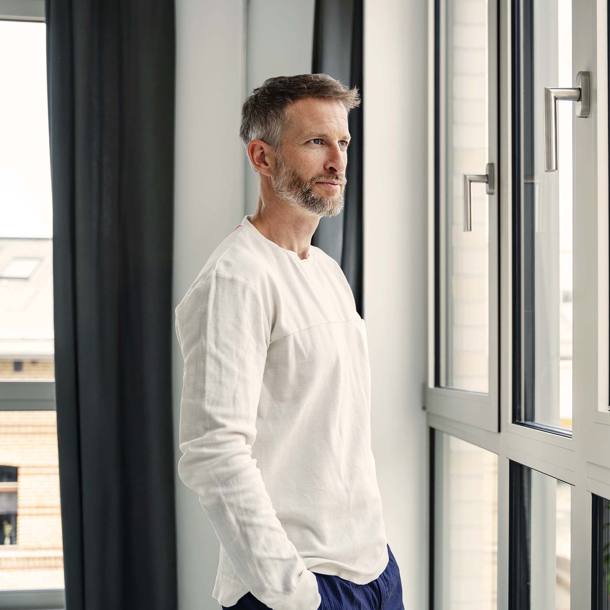 Thoughtful businessman n white shirt looking out office window