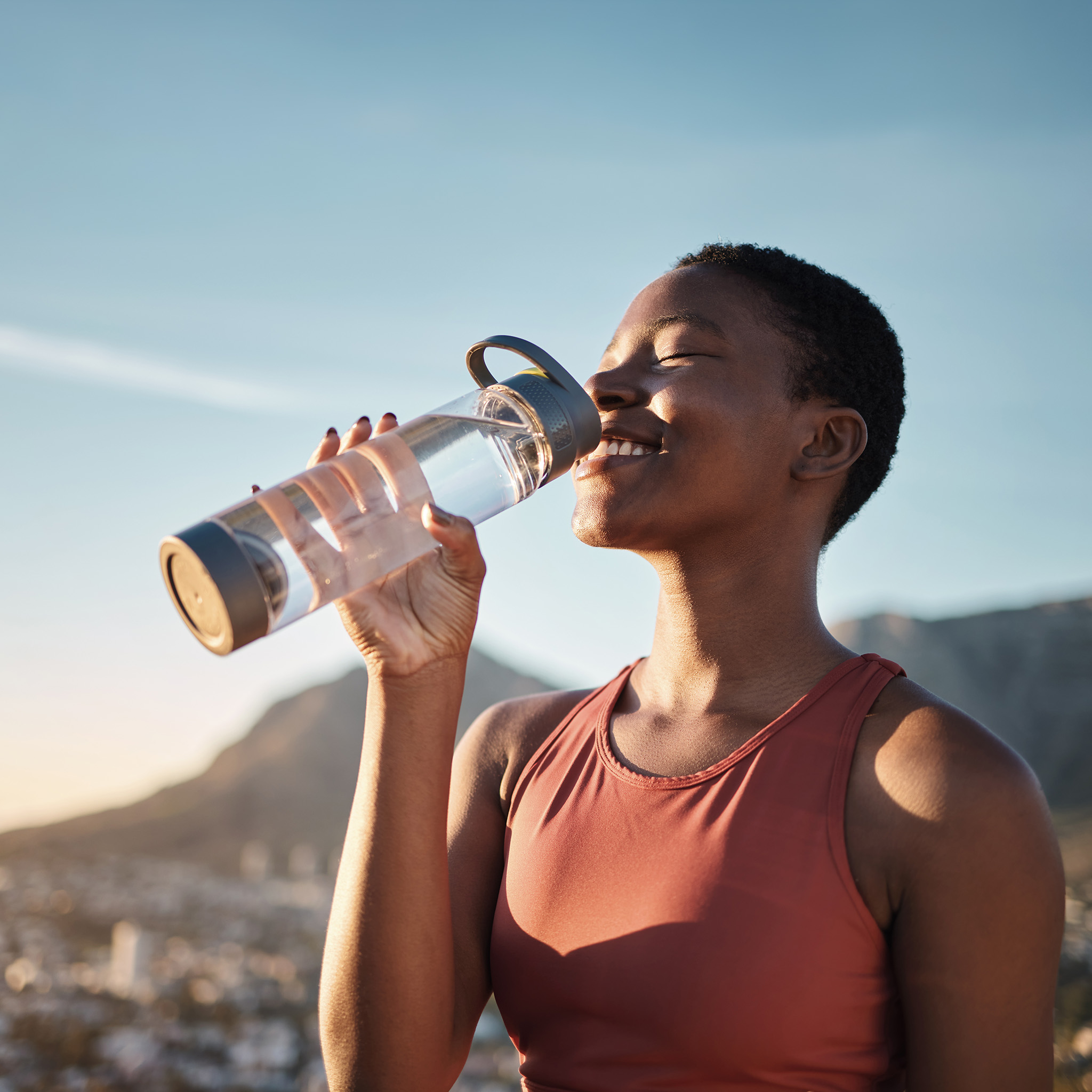 Black woman, runner and drinking water for outdoor exercise, training workout or marathon running recovery. African woman, healthy athlete and hydrate with bottle for fitness, health and cardio run