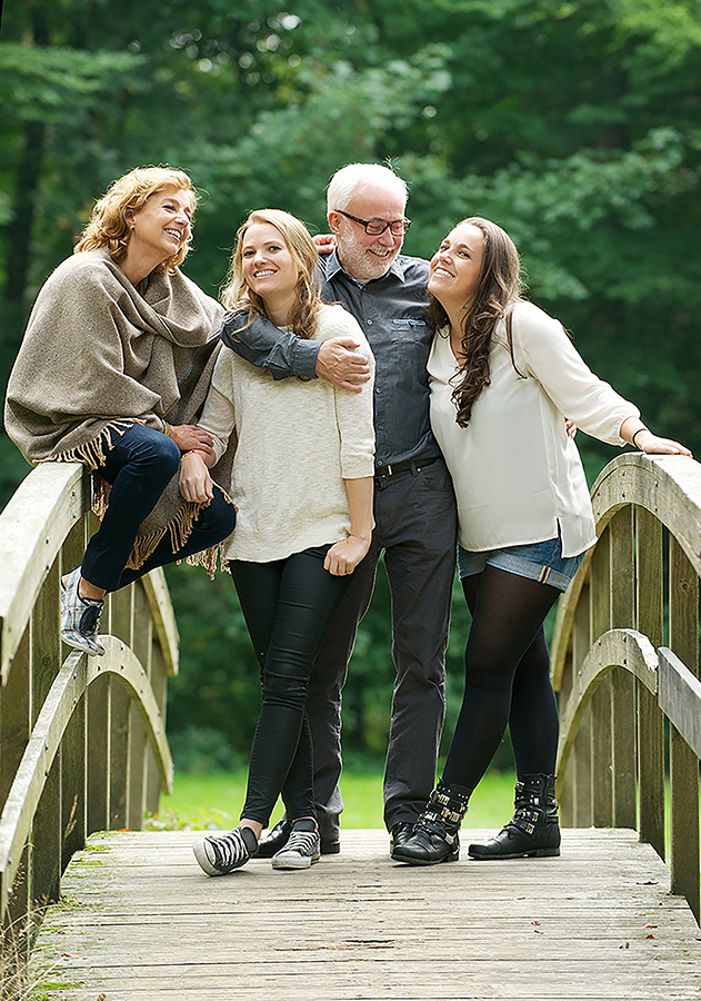 Beautiful happy family standing together in a bridge in the wood